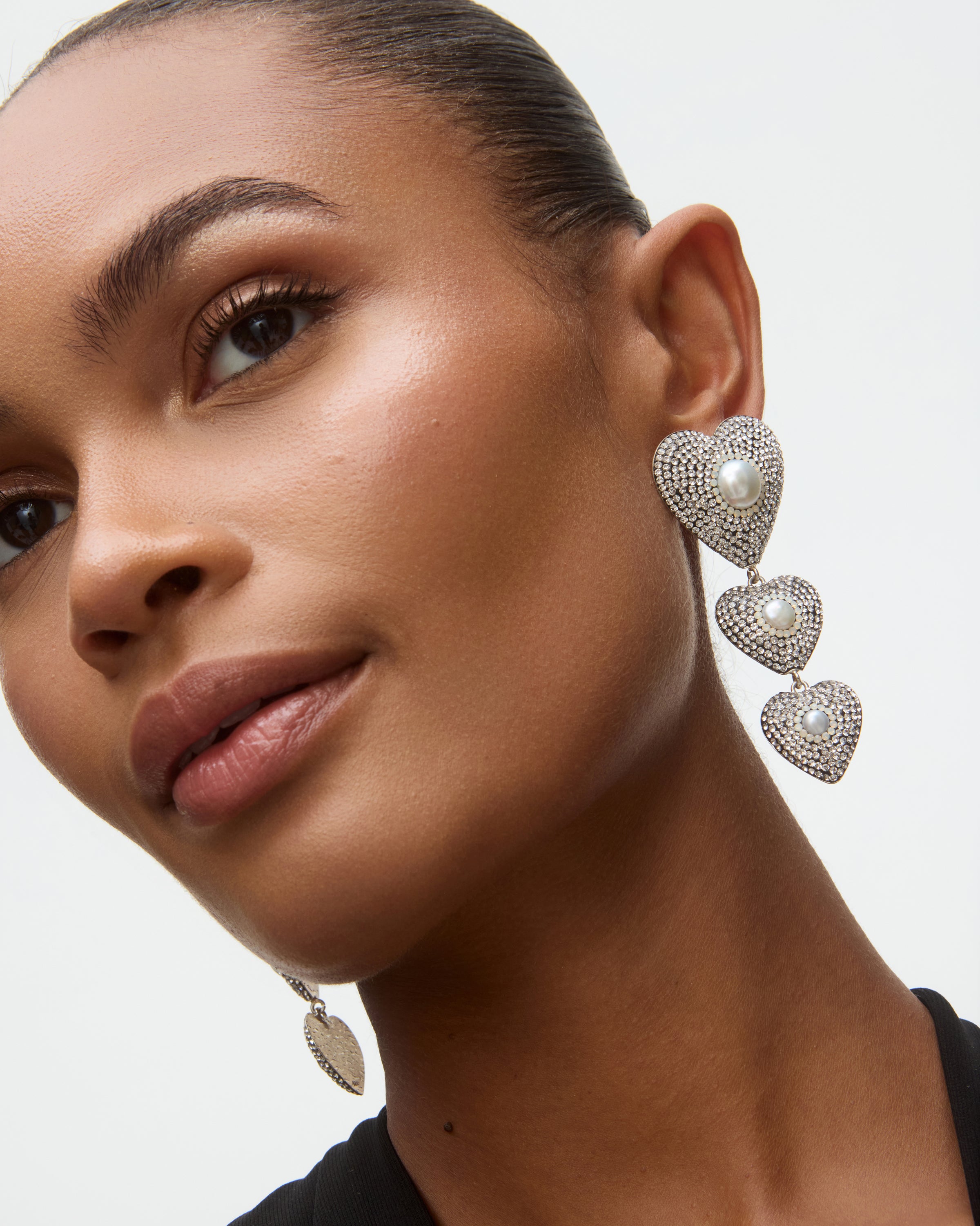 Close-up of a woman wearing heart-shaped earrings with a neutral background