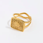 Gold ring with a textured sun design on a white background. 