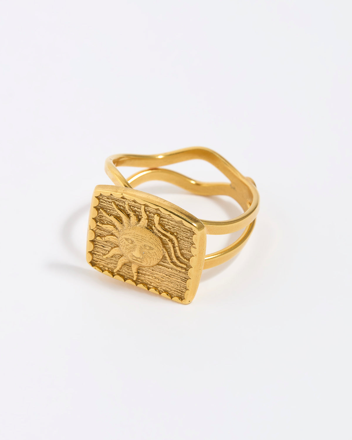 Gold ring with a textured sun design on a white background. 