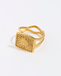 Gold ring with a textured sun design on a white background. 