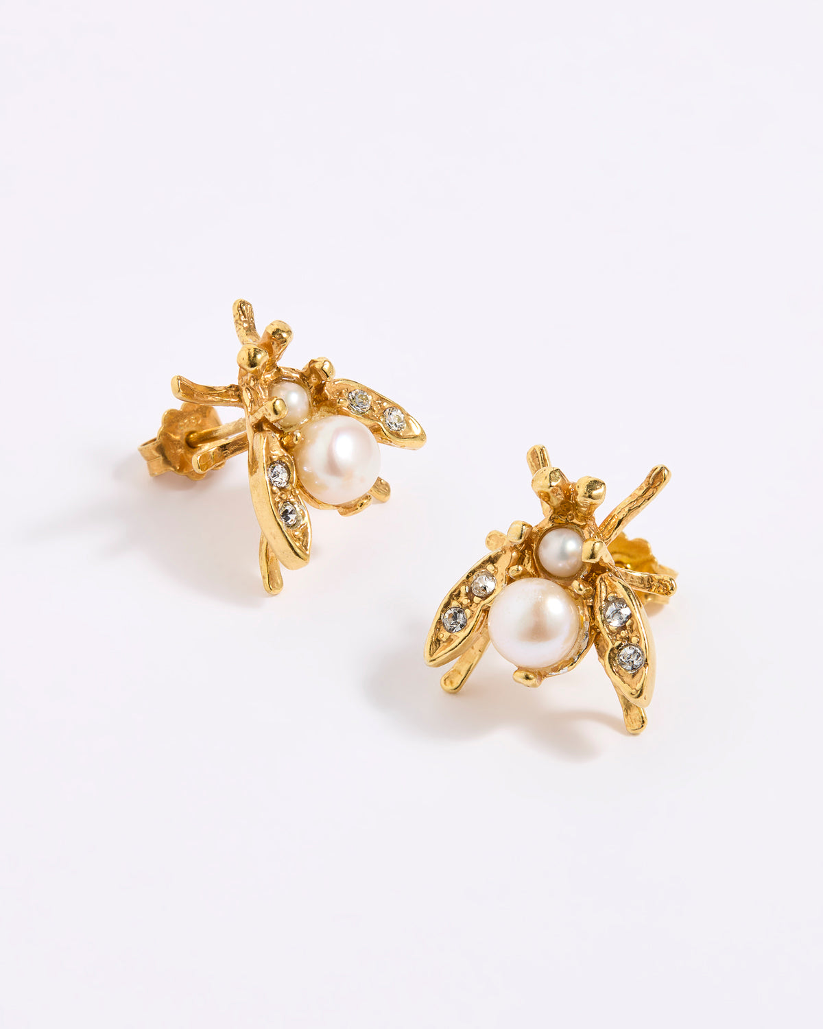 A pair of gold bee stud earrings with white  pearls and small clear rhinestones, displayed on a white background.