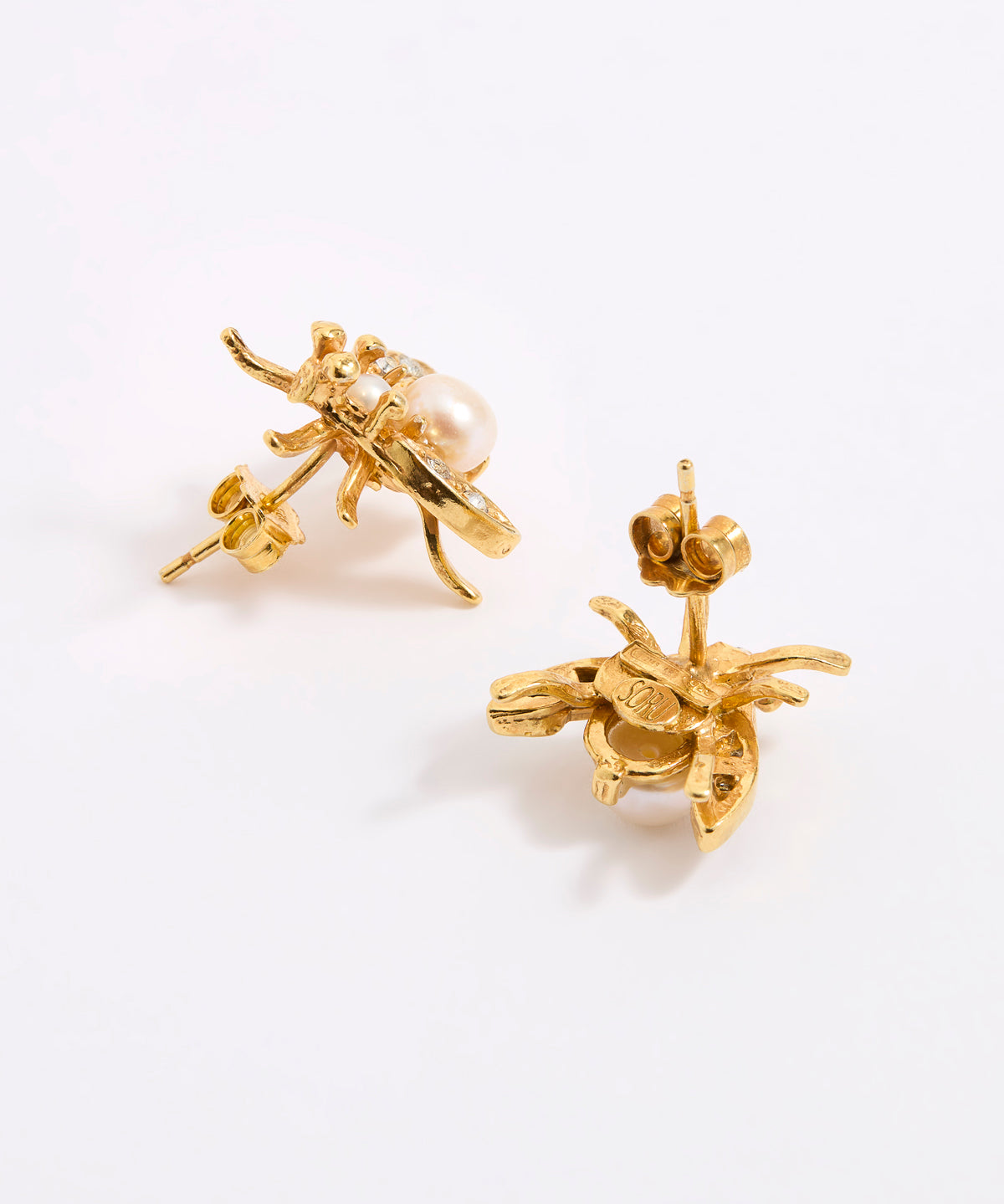 A pair of gold-tone bee stud earrings with a small white pearl, shown from the side and back on a white background.