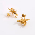 A pair of gold-tone bee stud earrings with a small white pearl, shown from the side and back on a white background.