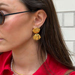 Close-up of a woman wearing gold coloured earrings with a shell design worn