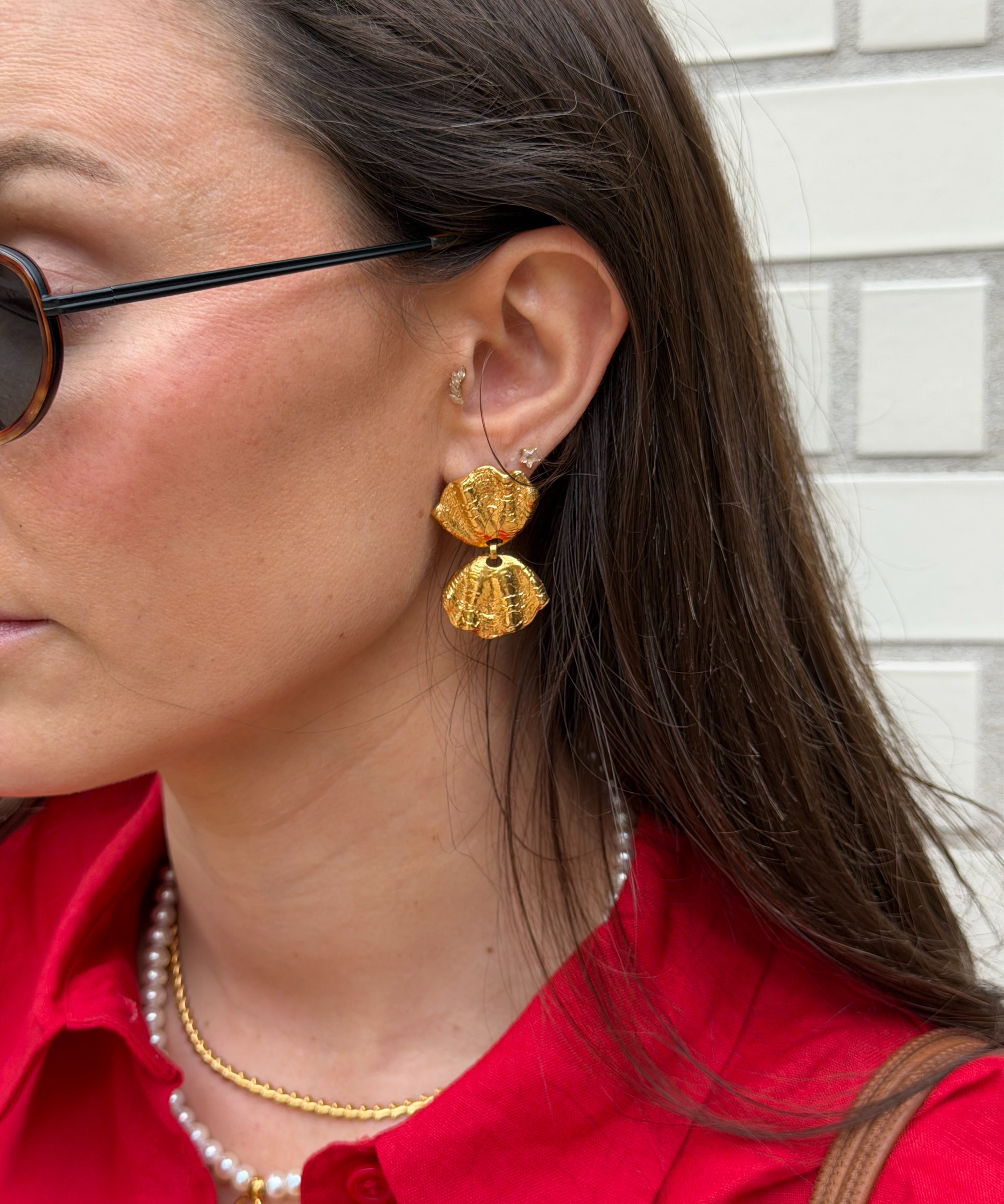 Close-up of a woman wearing gold coloured earrings with a shell design worn