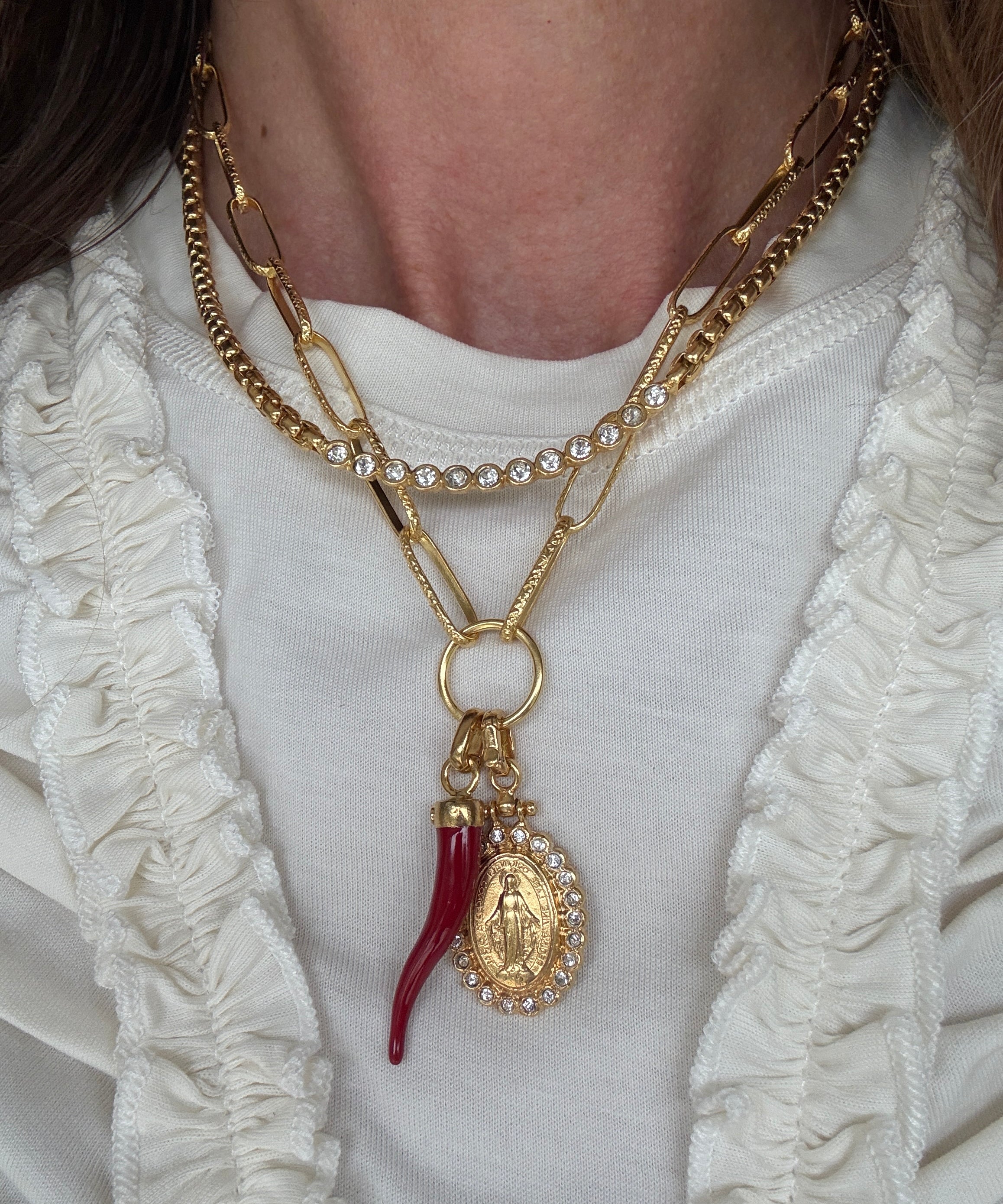Image of soru charm chain with madonna pendant and red cornucopia pendant charm  and soru scomo necklace around a neck