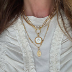 necklace layering set around a neck- the sun coin charm on a chain and the pellegrino necklace which has a madonna pendant attached and the como necklace 