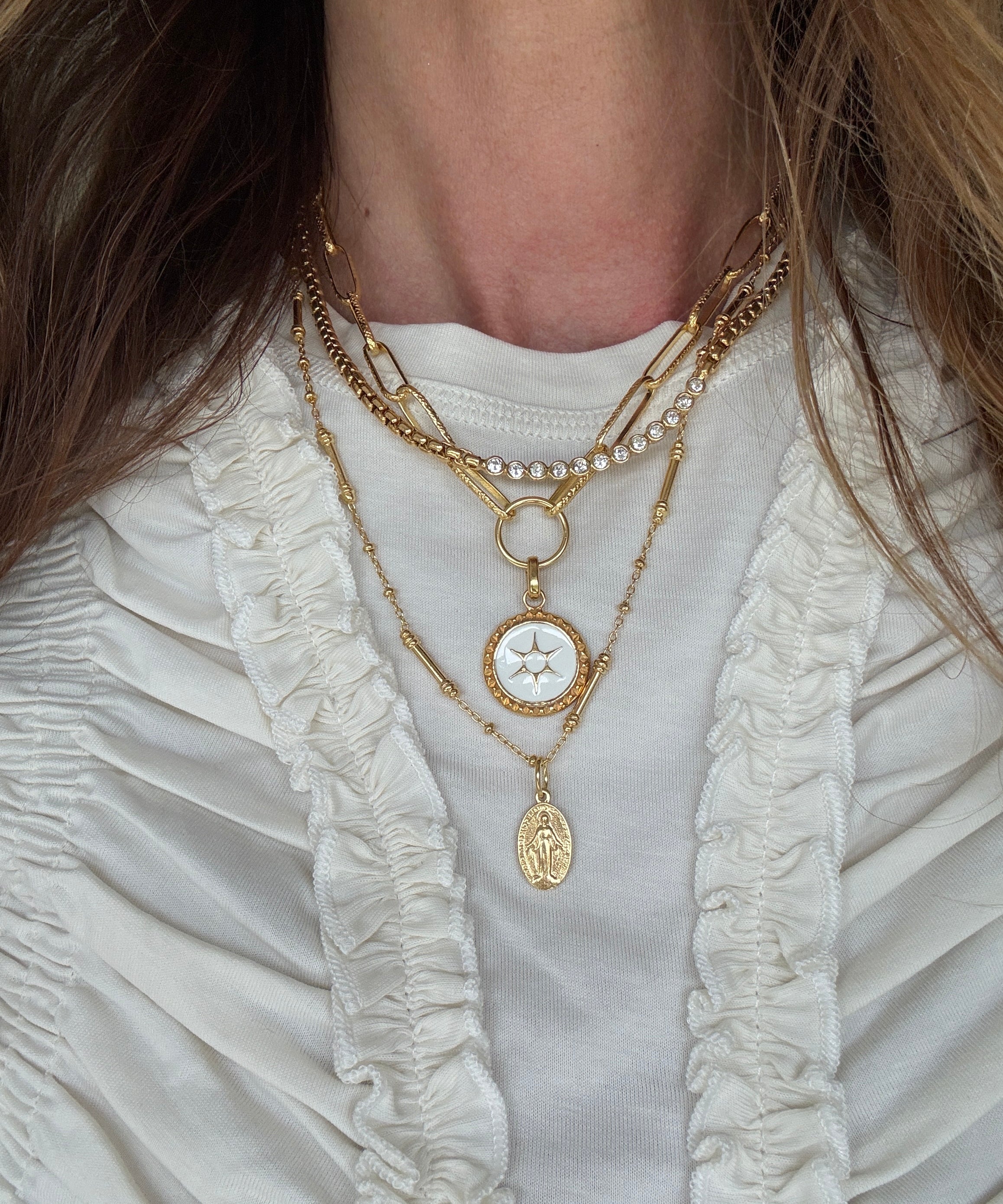 necklace layering set around a neck- the sun coin charm on a chain and the pellegrino necklace which has a madonna pendant attached and the como necklace 