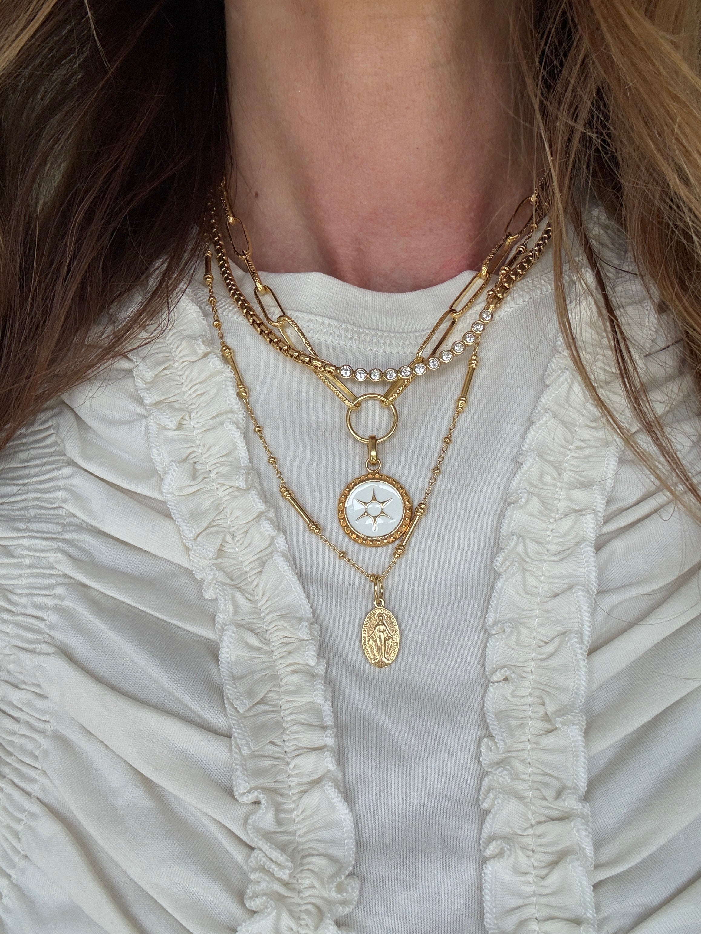 necklace layering set around a neck- the sun coin charm on a chain and the pellegrino necklace which has a madonna pendant attached and the como necklace 