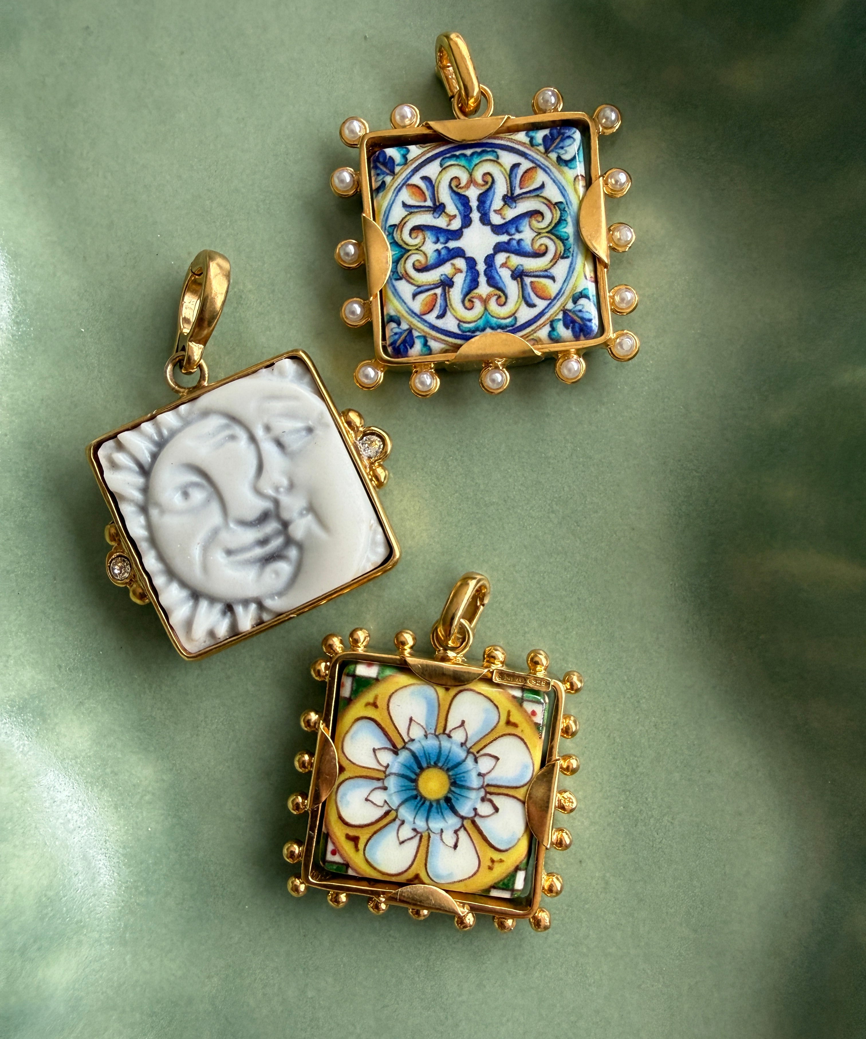 imgae of 3 square tile charms in a green ceramic tray- 2 tiles have colourful majolica and one is a sun and a moon in white ceramics