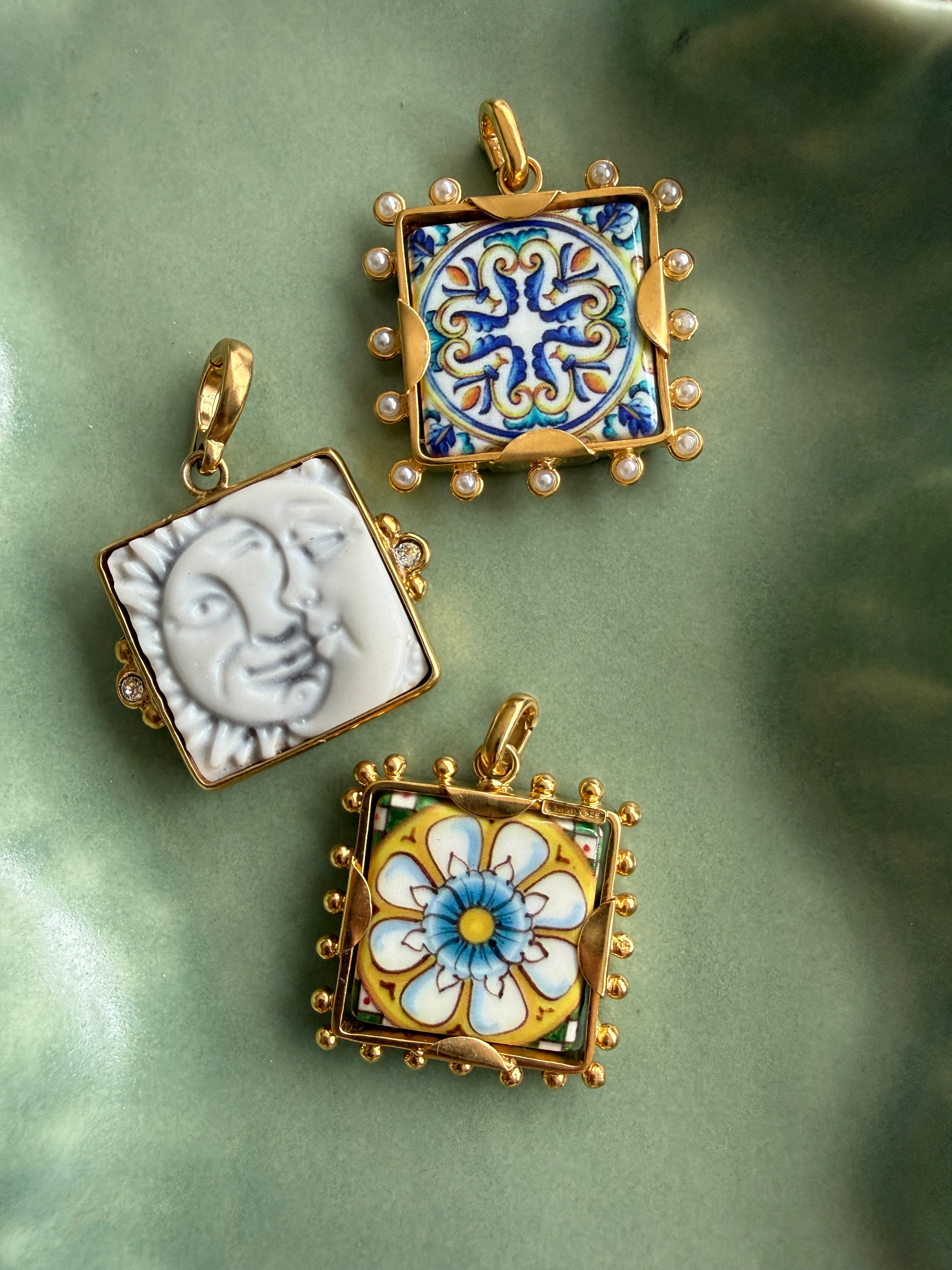 imgae of 3 square tile charms in a green ceramic tray- 2 tiles have colourful majolica and one is a sun and a moon in white ceramics