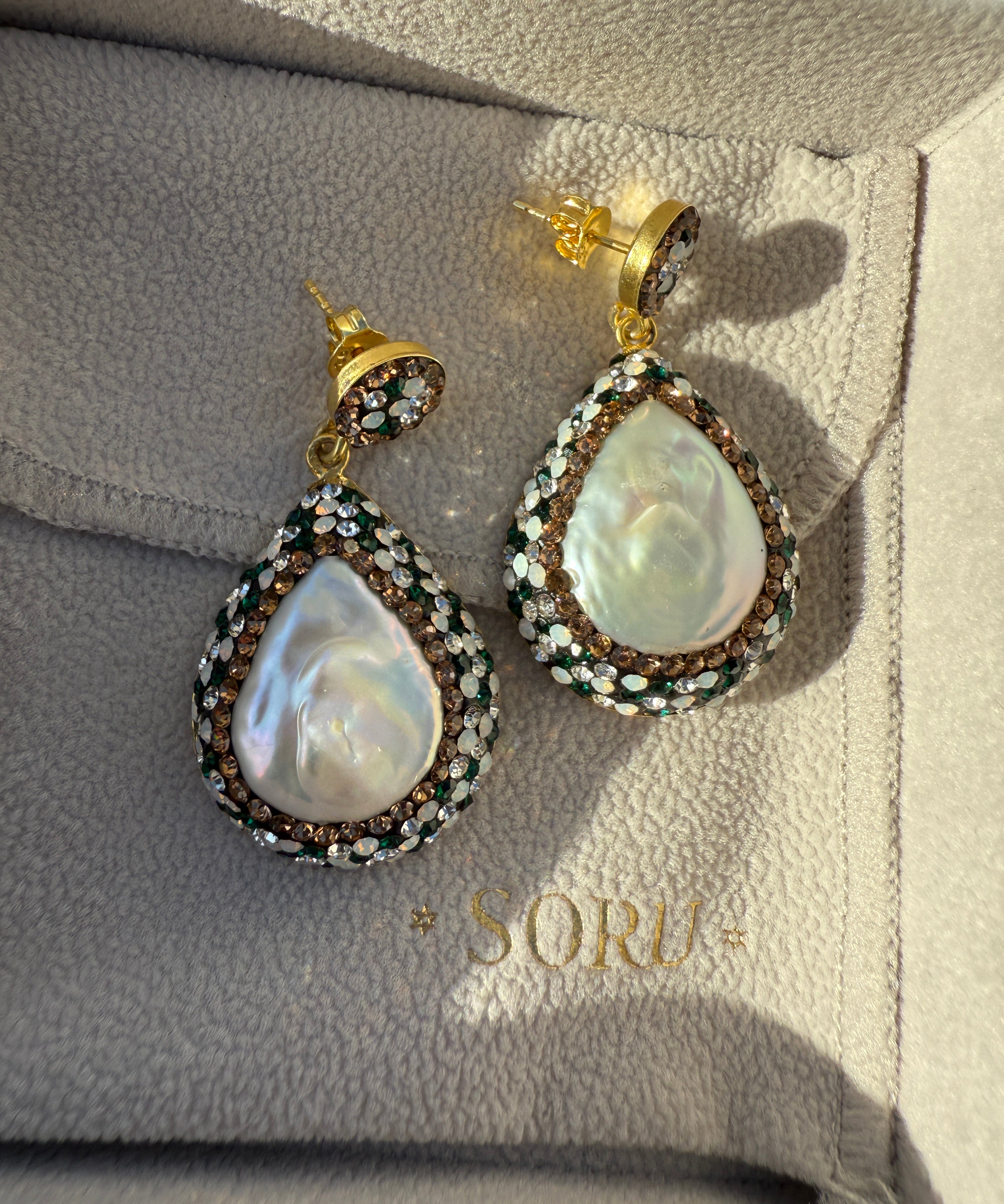 Pair of pearl earrings on a branded jewelry box