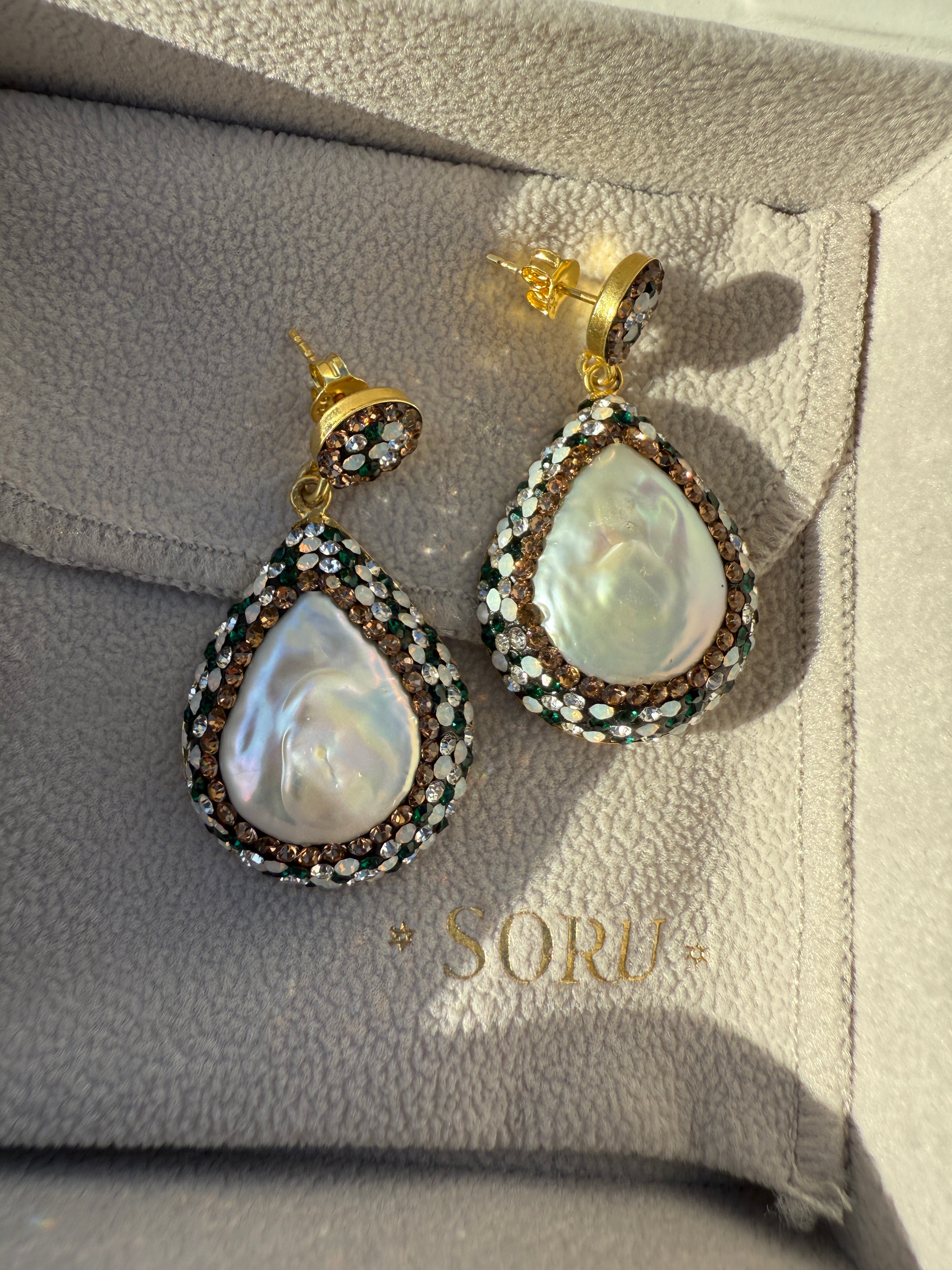 Pair of pearl earrings on a branded jewelry box
