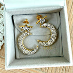 Gold and silver moon and star earrings on a SORU branded box.