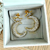 Gold and silver moon and star earrings on a SORU branded box.