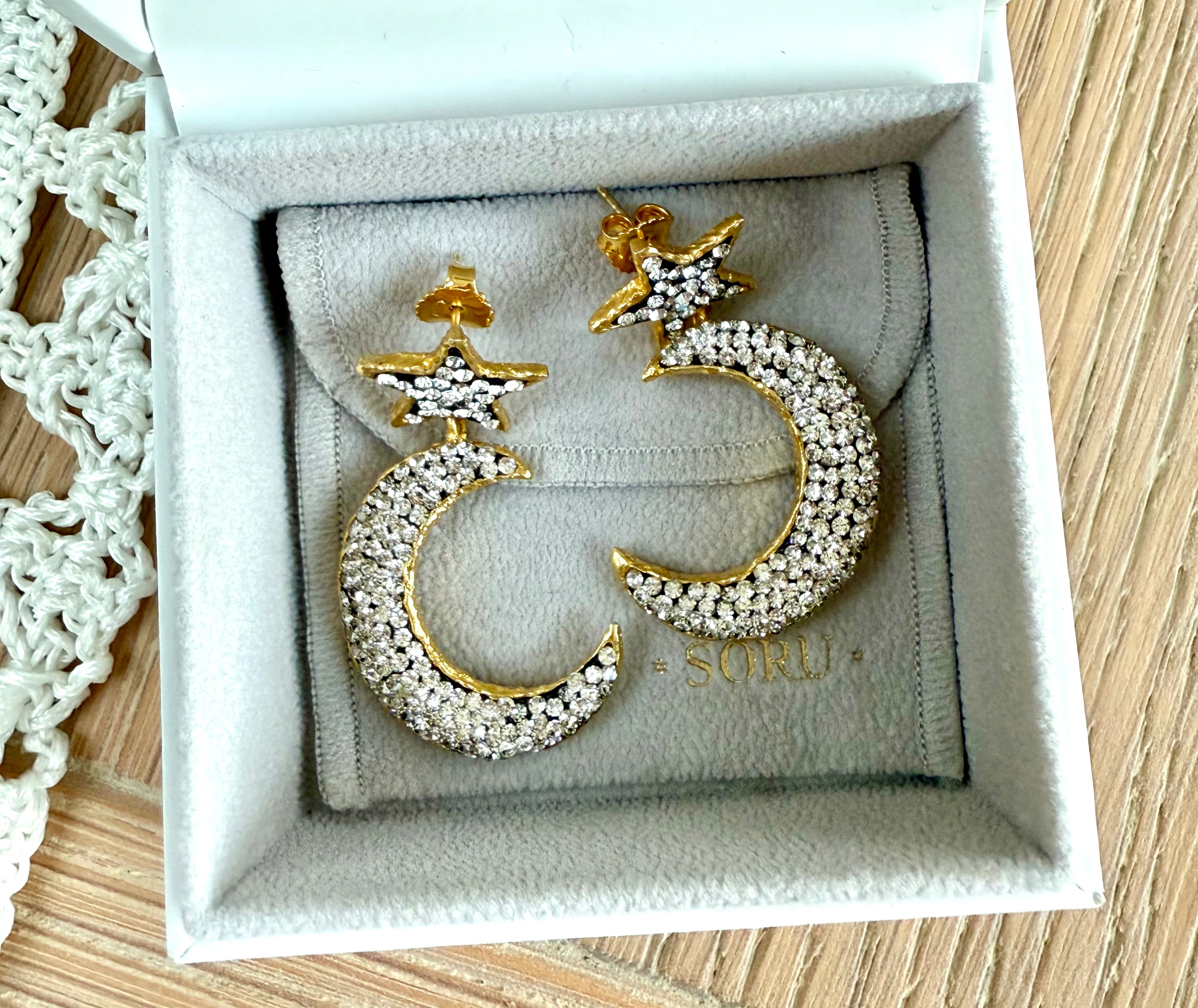 Gold and silver moon and star earrings on a SORU branded box.