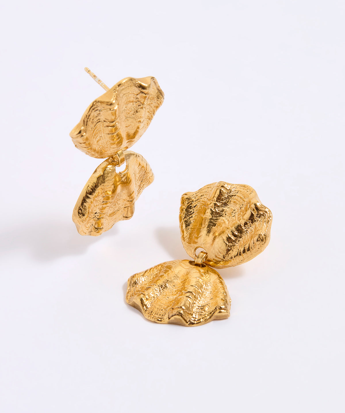 Gold coloured shell earrings on a light gray background