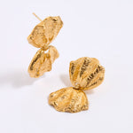 Gold coloured shell earrings on a light gray background