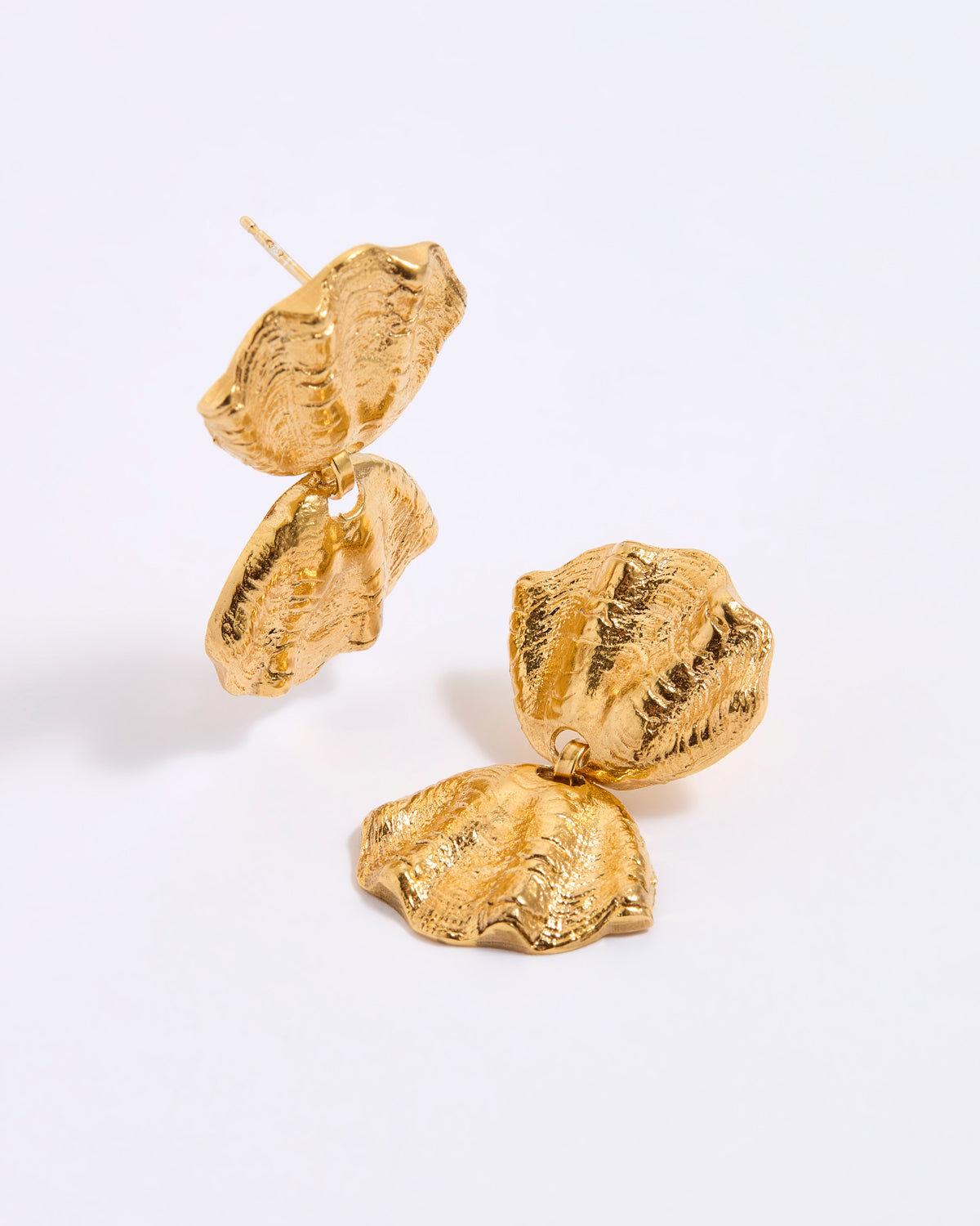 Gold coloured shell earrings on a light gray background