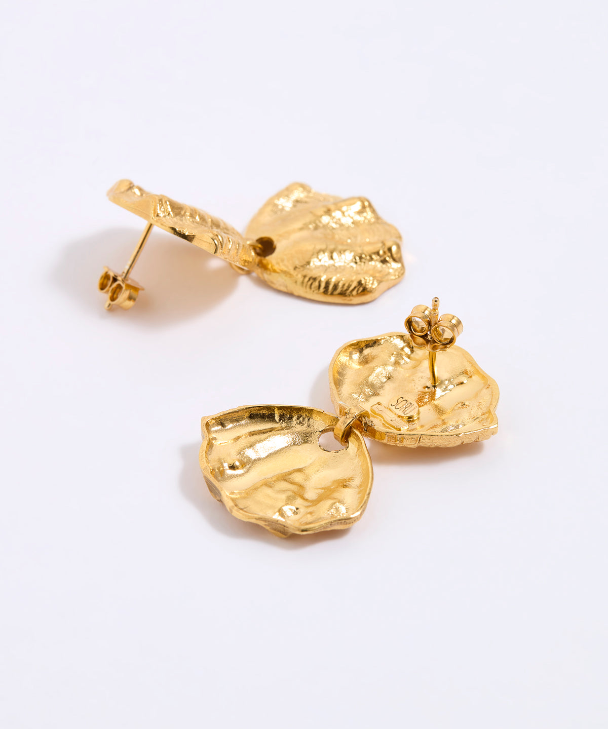 Gold earrings on a light gray background