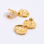 Gold earrings on a light gray background