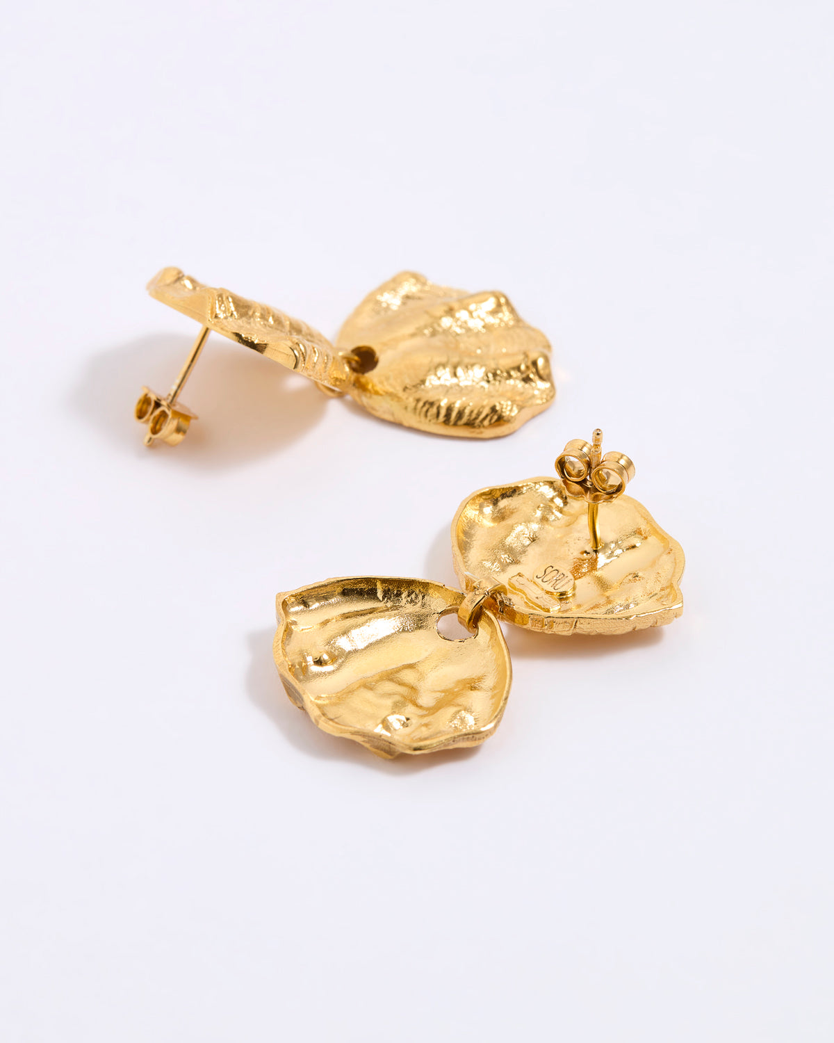 Gold earrings on a light gray background