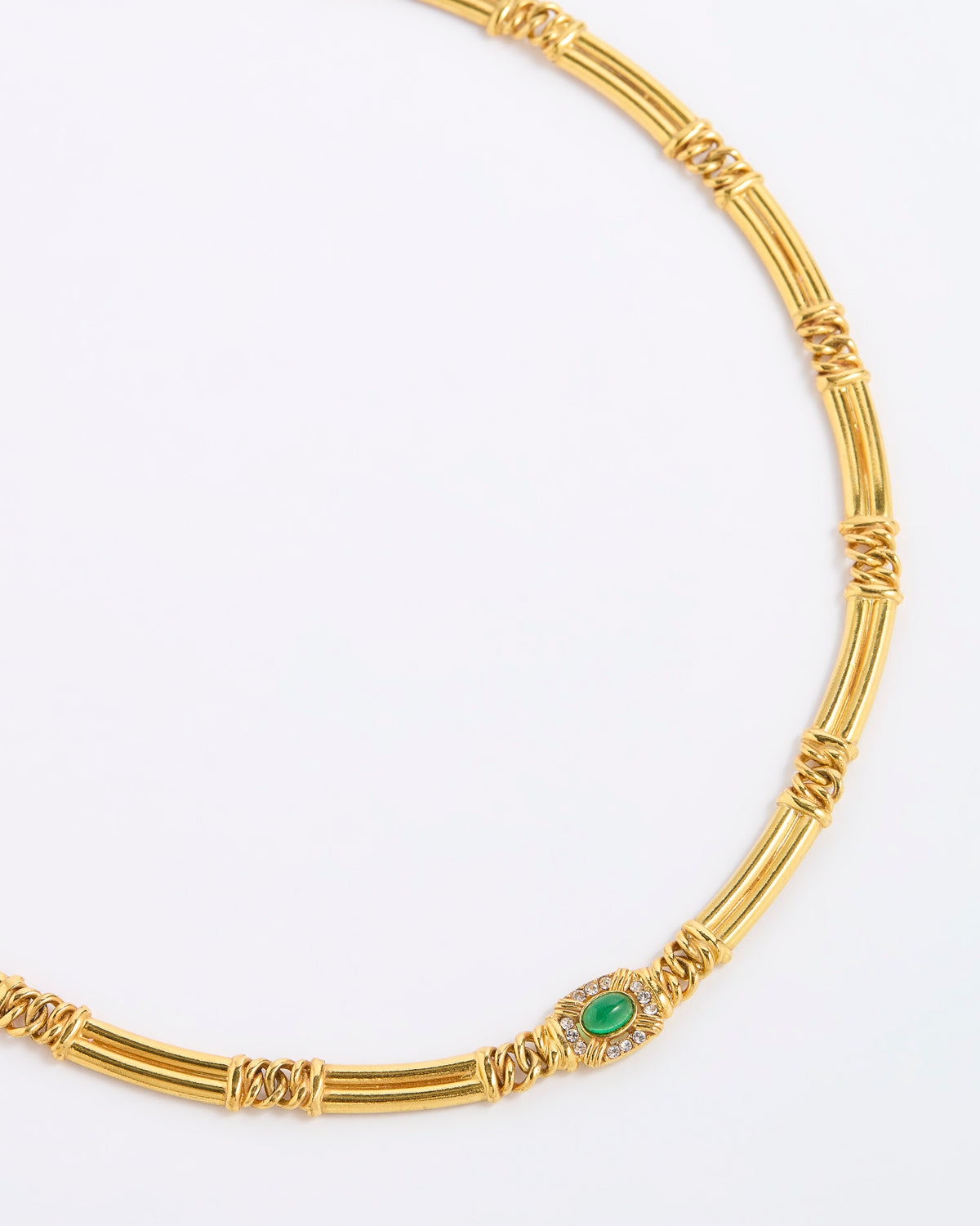 A gold-toned necklace with a distinctive segmented, twisted bamboo-like design and a central oval green stone surrounded by small clear stones, shown on a plain white background.