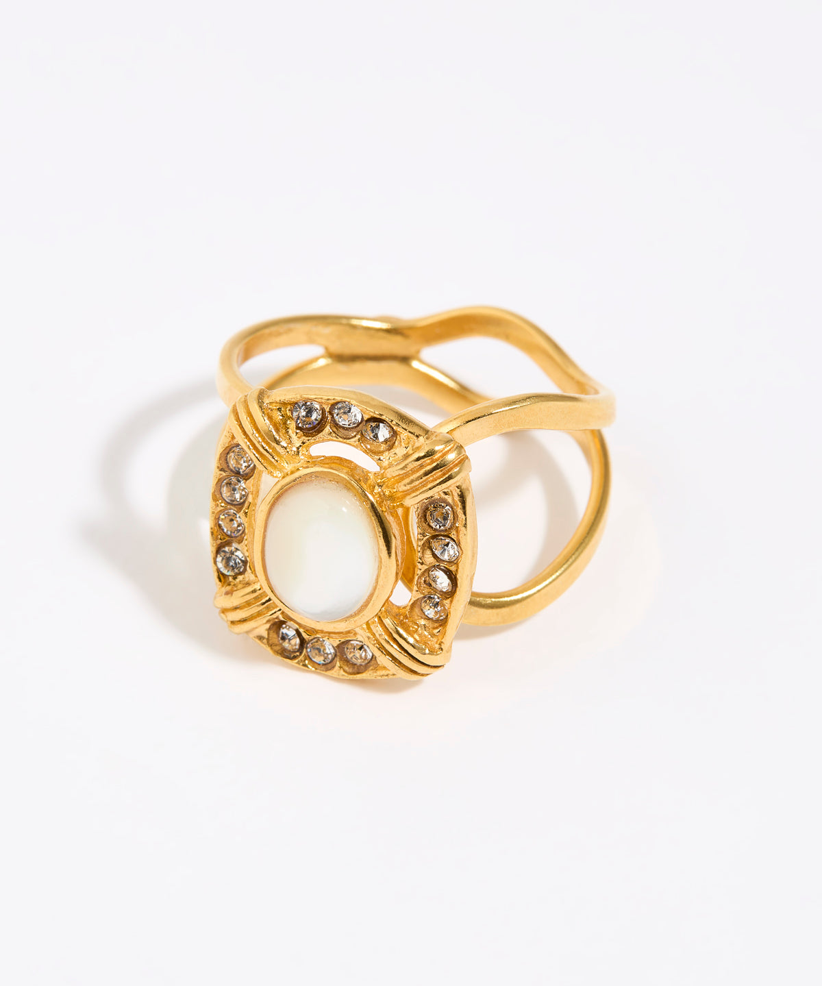 Gold ring featuring an oval moonstone surrounded by small crystals in a square setting