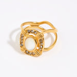 Gold ring featuring an oval moonstone surrounded by small crystals in a square setting
