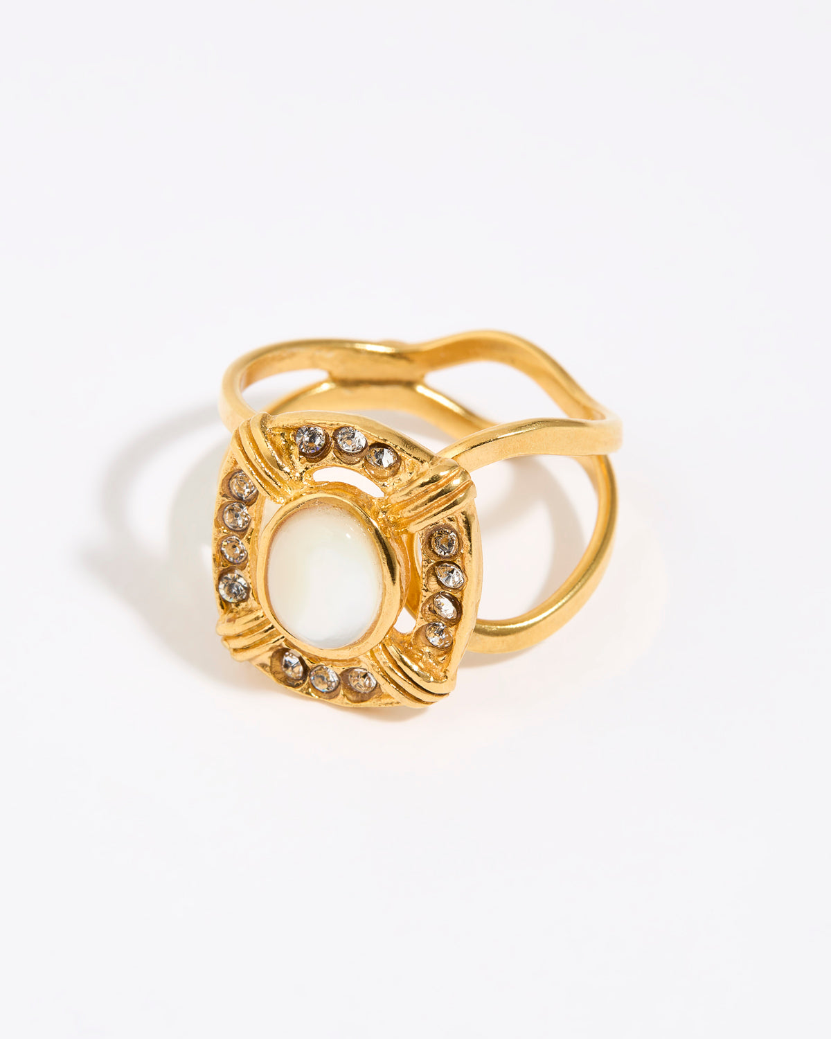 Gold ring featuring an oval moonstone surrounded by small crystals in a square setting