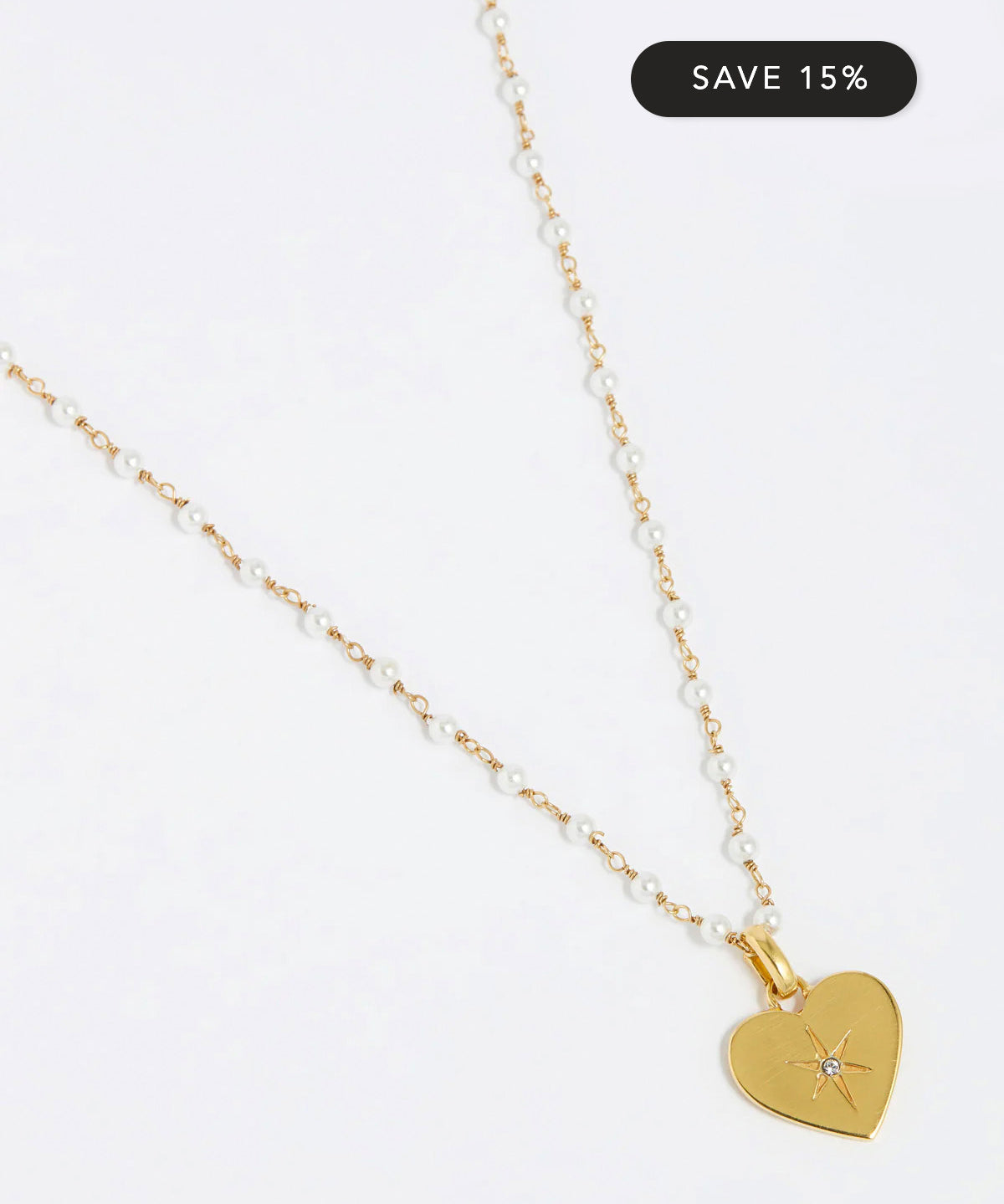 Image of pearl charm neckace, the charm features a clear crystal surrounded by a star etching set in a shiny gold heart.