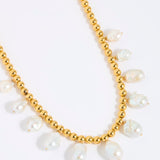 Gold beaded necklace with statement white pearls on a white background