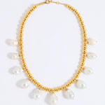 Gold necklace with white pearls on a white background