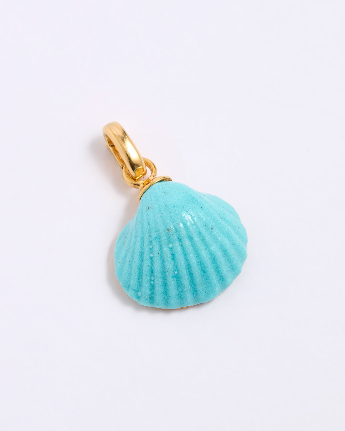 Turquoise shell pendant with gold coloured clasp on a light gray background