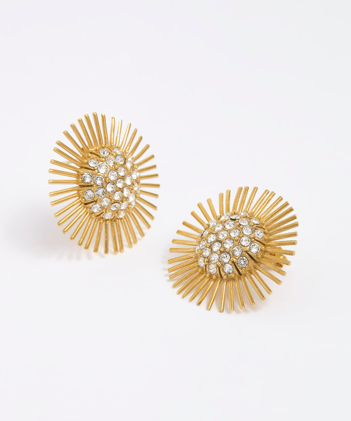 Close-up product image of gold sunburst earrings with rhinestone centres on a white background