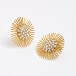 Close-up product image of gold sunburst earrings with rhinestone centres on a white background