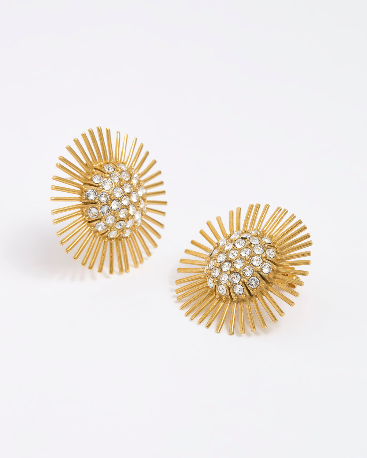 Close-up product image of gold sunburst earrings with rhinestone centres on a white background