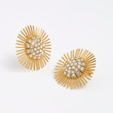 Close-up product image of gold sunburst earrings with rhinestone centres on a white background