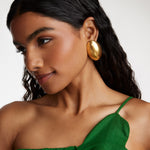 side view model shot wearing the Soru Jewellery gold oversized textured oval earrings while model is smiling