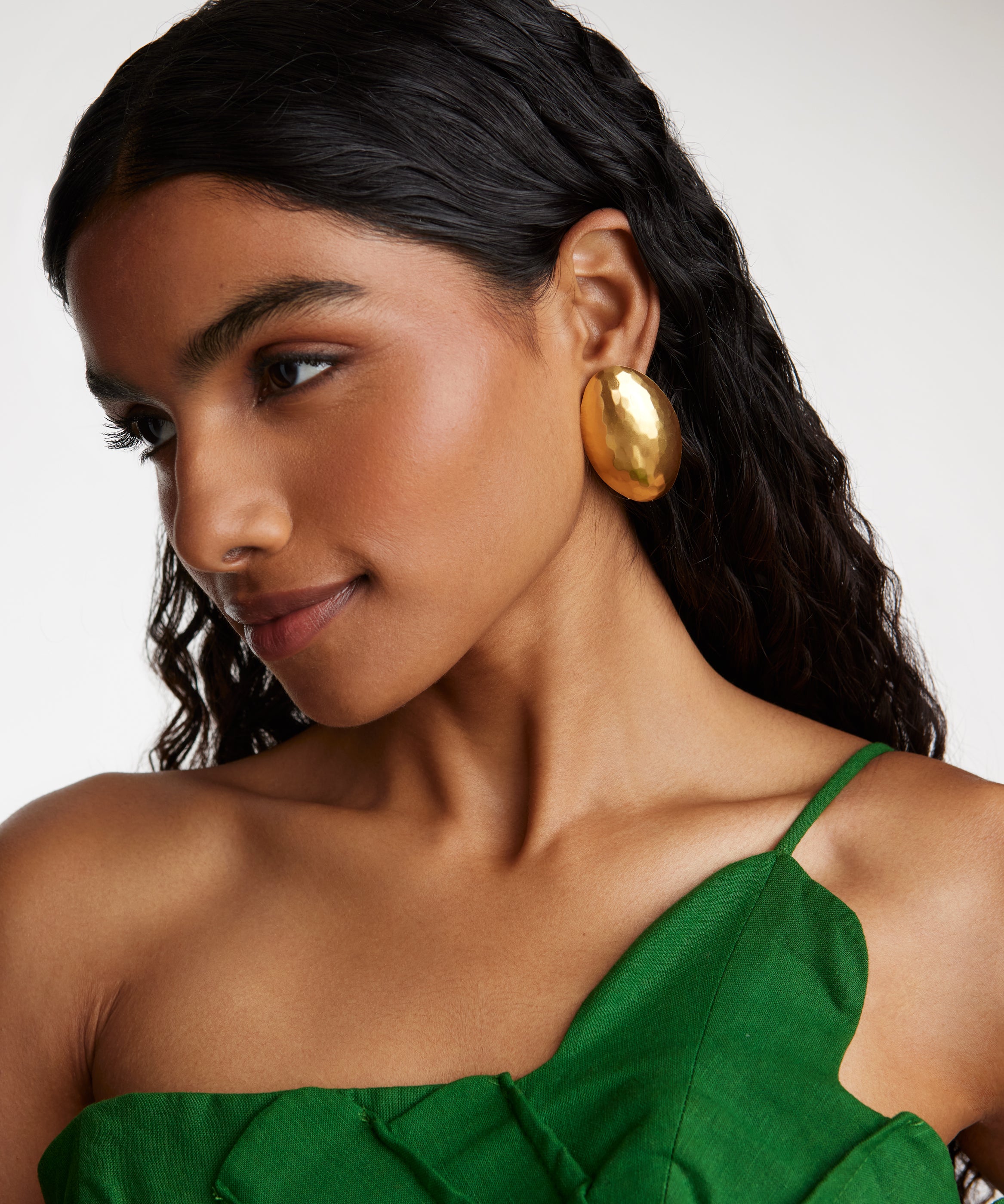 side view model shot wearing the Soru Jewellery gold oversized textured oval earrings while model is smiling
