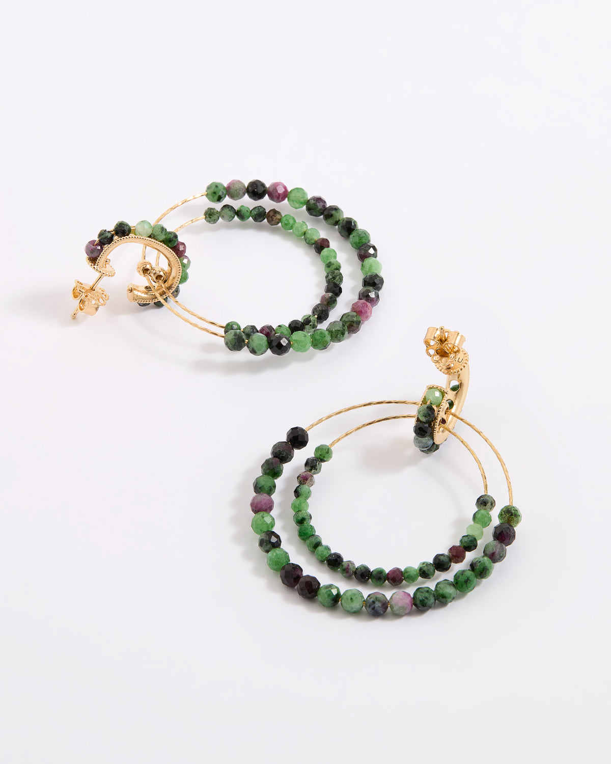 A pair of delicate gold double-hoop earrings, adorned with multiple strands of small, faceted beads in rich shades of green, dark charcoal, and purple, displayed against a white background.