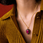 Ruby pear shaped pendant necklace on gold chain with crystal boarder shown close up on models neck 