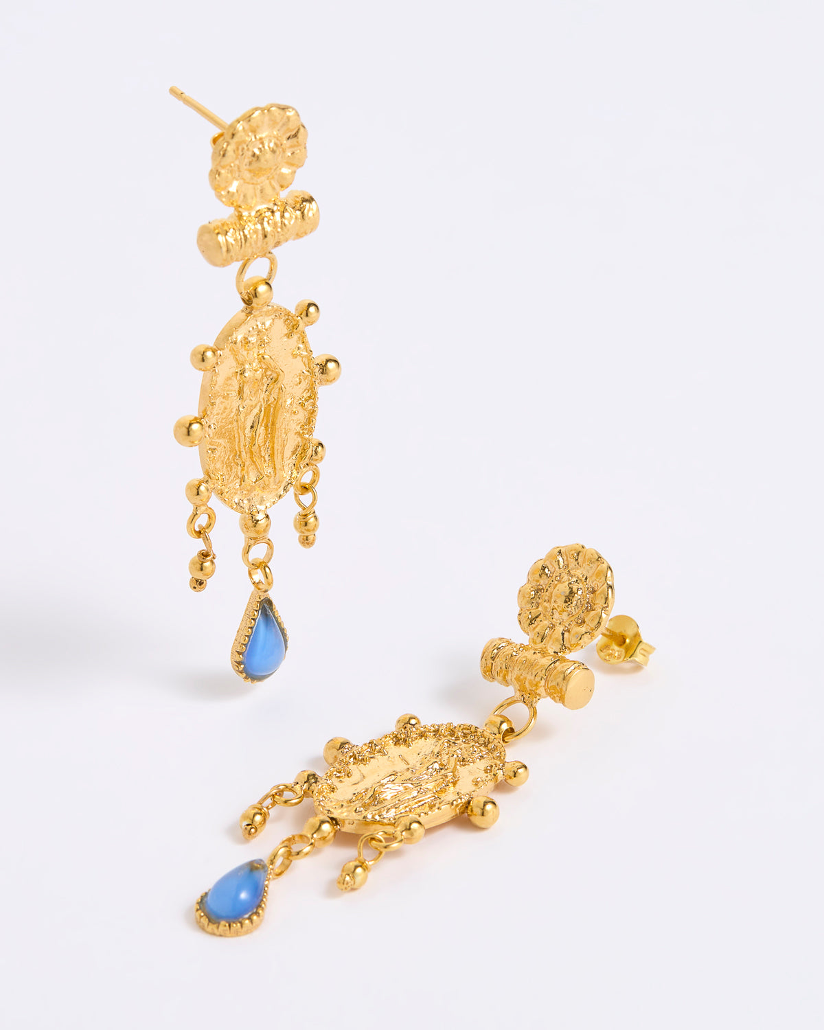 A pair of gold-toned statement dangle earrings with textured baroque-style charms and light blue teardrop accents, displayed on a white background.