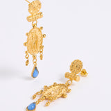 A pair of gold-toned statement dangle earrings with textured baroque-style charms and light blue teardrop accents, displayed on a white background.