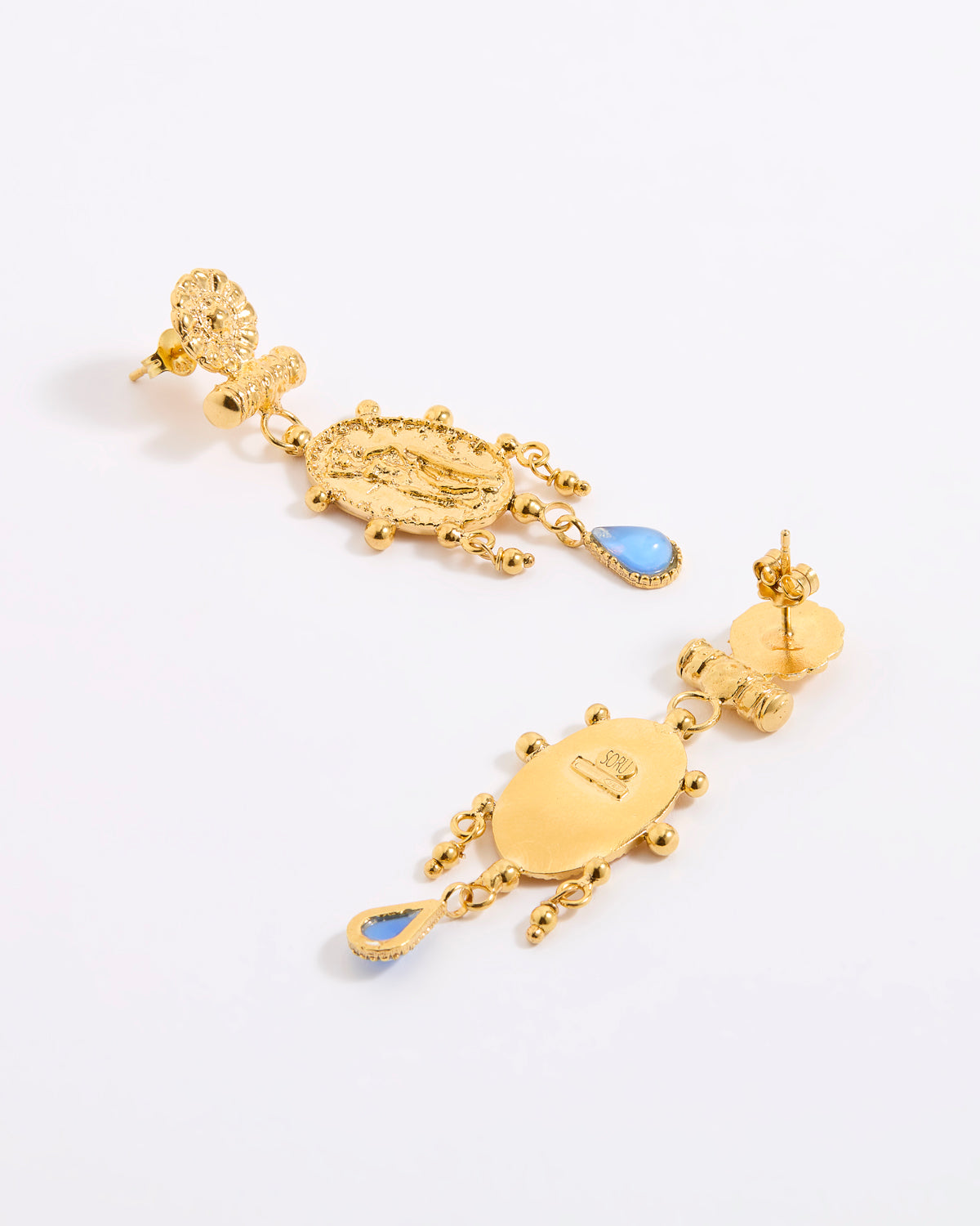 Reverse and front image of a pair of earrings, feature Oval, organically finished medallion featuring the figure of a woman. Handmade with classic detailing and a decorative border, finished with a delicate pale blue hanging glass cabochon.