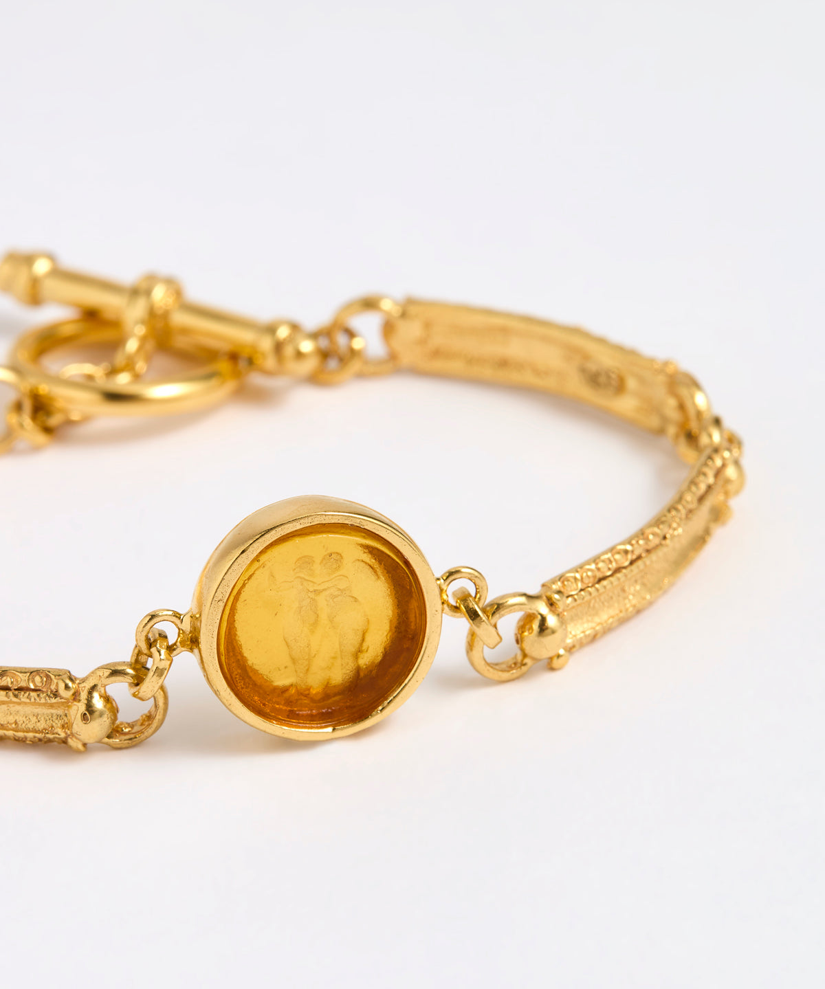 Close up of Gold link bracelet with round pendant in the centre with amber  glass