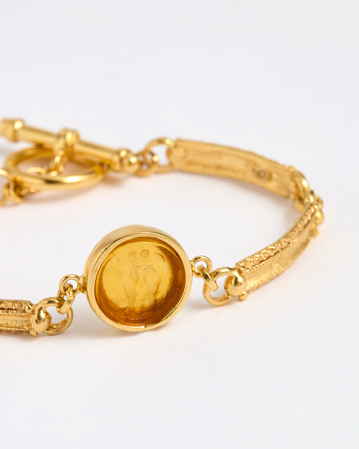 Close up of Gold link bracelet with round pendant in the centre with amber  glass