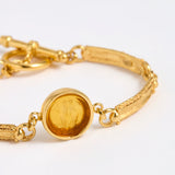 Close up of Gold link bracelet with round pendant in the centre with amber  glass