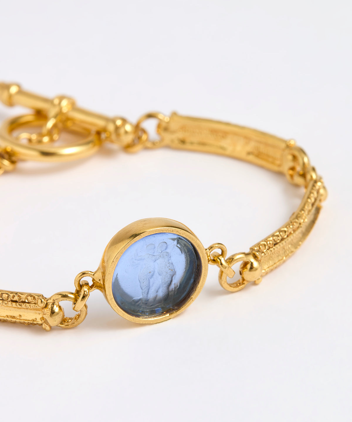 Close up Gold link bracelet with round pendant in the centre with blue glass 