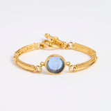 Gold link bracelet with round pendant in the centre with blue glass 
